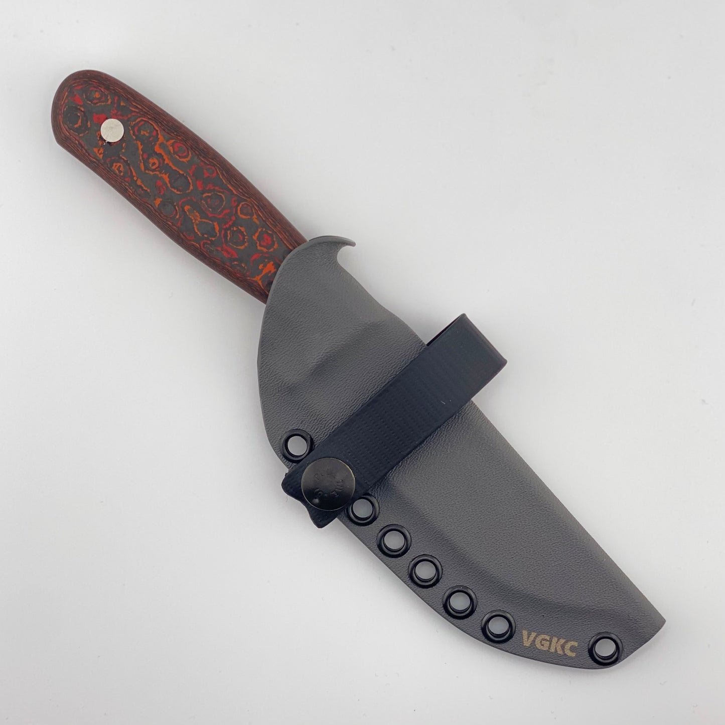 Fixed blade knife with red, orange, and black handle in a black sheath with a black strap on a white background