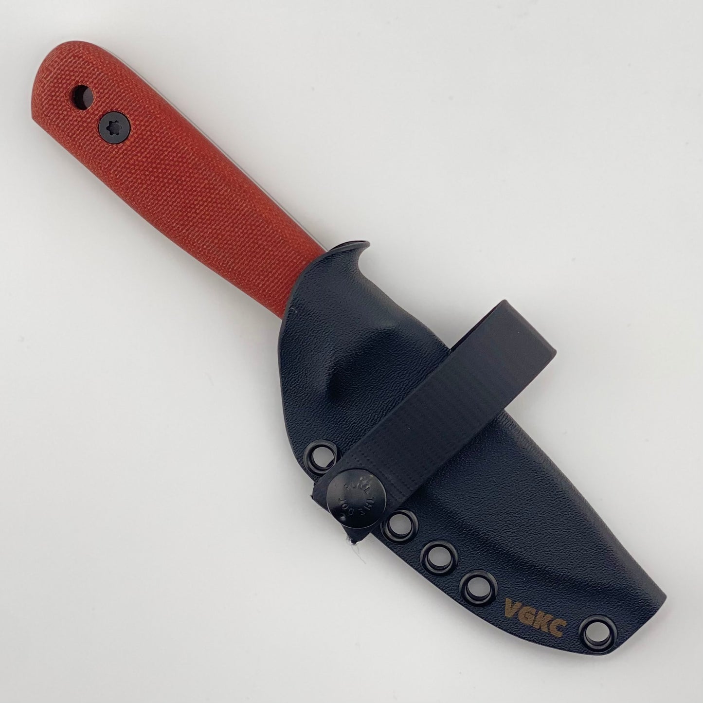 Red handled knife in a black sheath on a white background