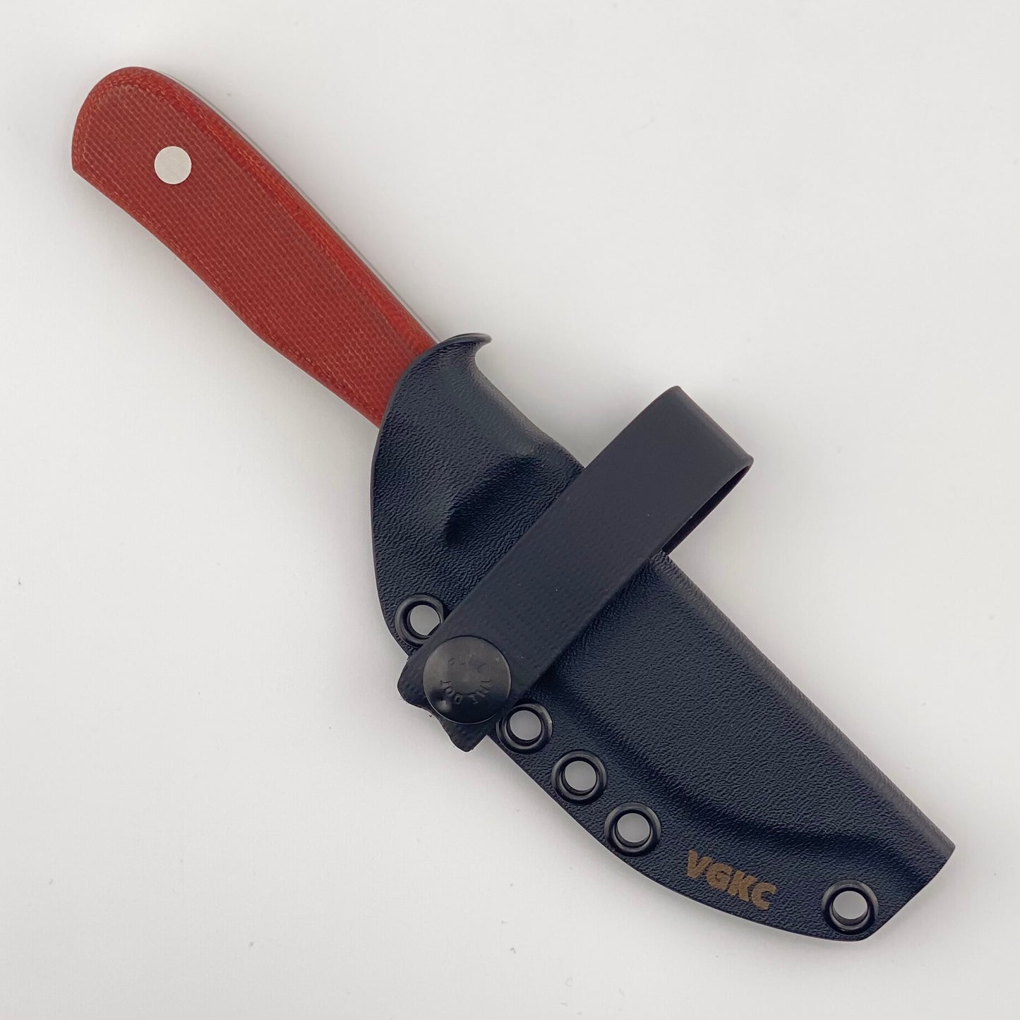 Fixed b lade knife with red handles in a back sheath with a black strap on a white background