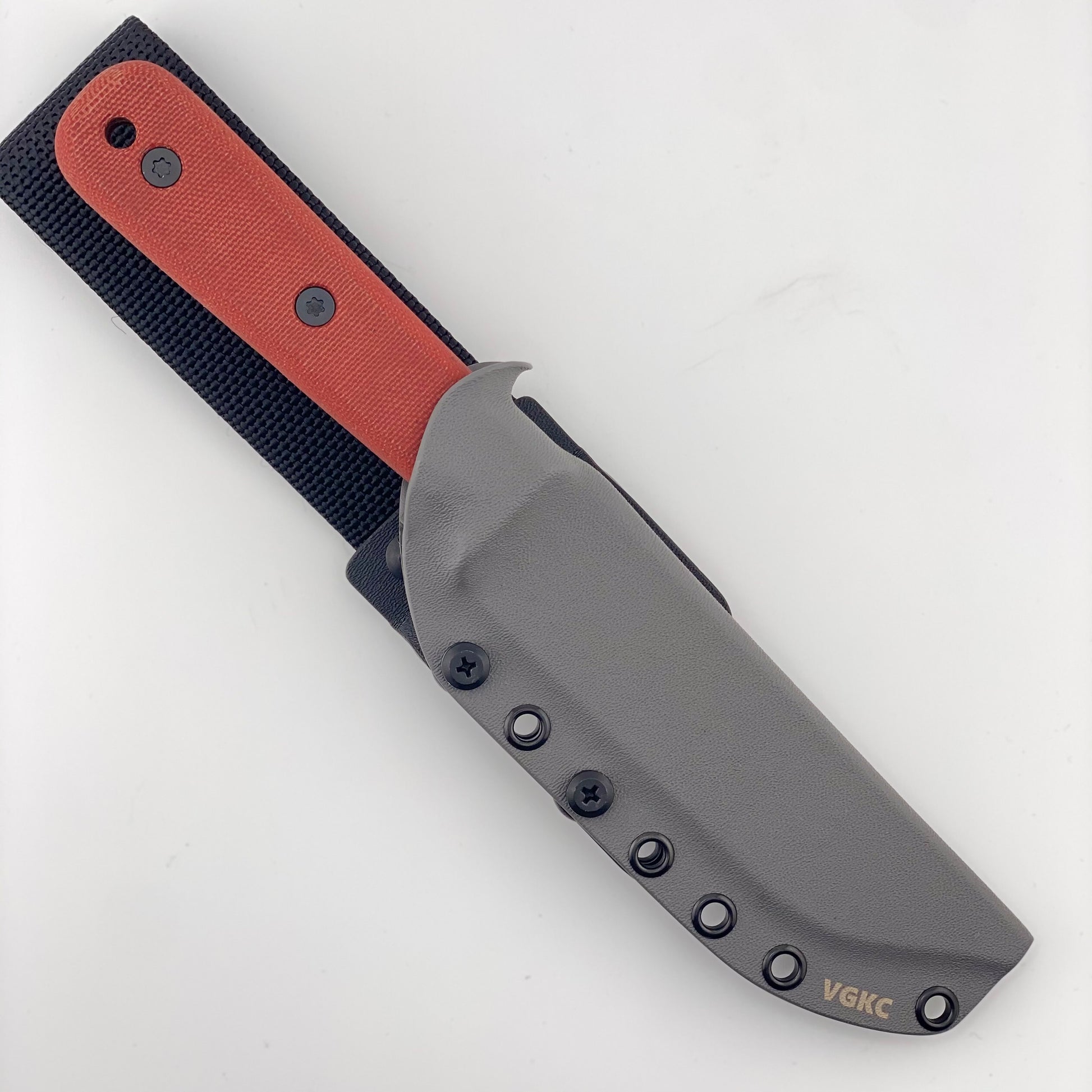 Fixed blade knife with red handles in a gray sheath on a white background